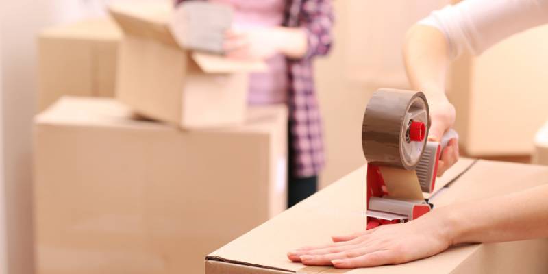 Sealing a box with tape to illustrate a step of the pick, pack and ship service provided by fulfilment companies