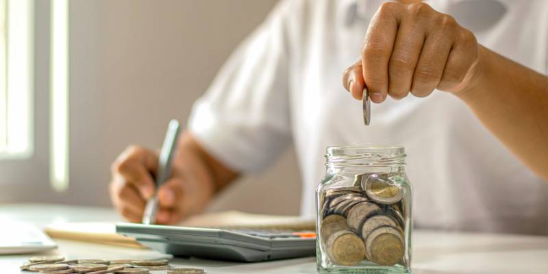 Putting coins in a jar while reviewing increased shipping costs.