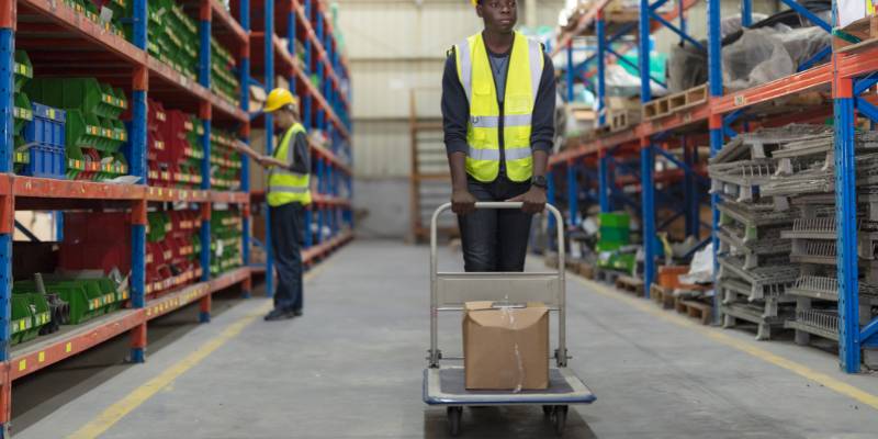 Employee pushing cart in warehouse with a package in the picking process of the fulfillment process.