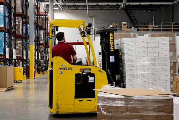 Man using a forklift to move pallets of product around