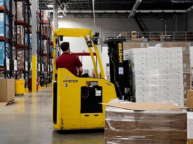 Man using a forklift to move pallets of product around